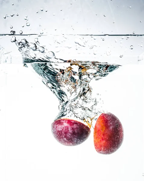 plum in water with splash and cut in half