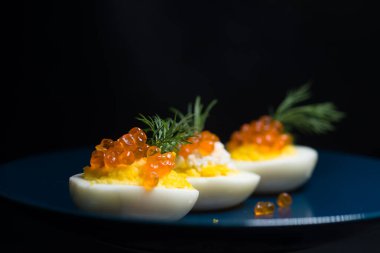 Kırmızı havyarla doldurulmuş yumurtalar lezzetli ve sağlıklı. Bir restoranda mavi tabakta servis edilen Paskalya için en iyi yemek.