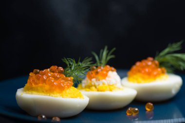 Kırmızı havyarla doldurulmuş yumurtalar lezzetli ve sağlıklı. Bir restoranda mavi tabakta servis edilen Paskalya için en iyi yemek.