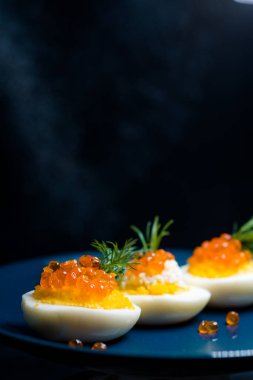 Kırmızı havyarla doldurulmuş yumurtalar lezzetli ve sağlıklı. Bir restoranda mavi tabakta servis edilen Paskalya için en iyi yemek.