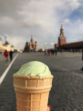 Moskova-Rusya 'daki Kızıl Meydan' ın arka planında Pistachio dondurması. İnanılmaz St. Basil Katedrali ve Spasskaya Kulesi. Mavi gökyüzü ve turistler. Solda Katedral Meydanı var..