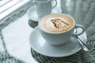 Beyaz fincan cappuccino seçici odak masada duruyor.
