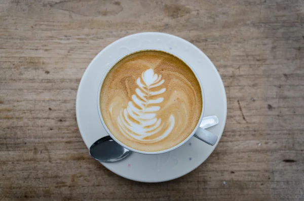 Kopje warme koffie latte kunst op houten tafel — Stockfoto