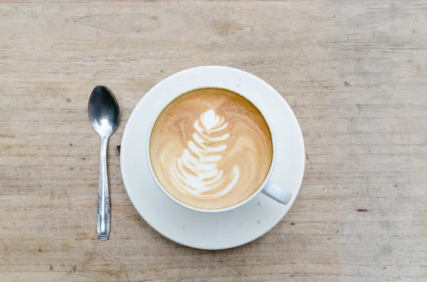 Kopje warme koffie latte kunst op houten tafel — Stockfoto
