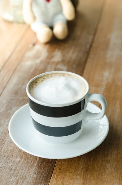 Klassieke schuimige cappuccino in een cup op houten tafel — Stockfoto