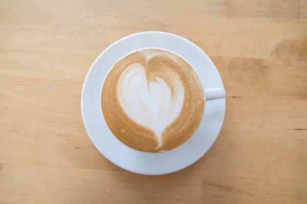 Kopje warme koffie latte kunst op houten tafel — Stockfoto