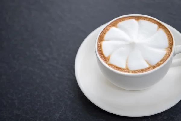 Hete kunst latte koffie in cup op zwarte tabel — Stockfoto