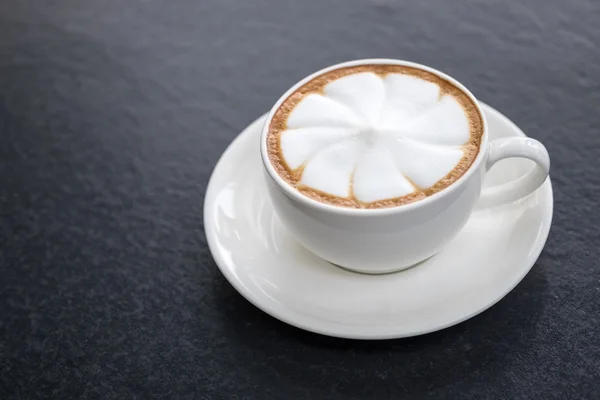 Café latte arte caliente en taza en mesa negra — Foto de Stock