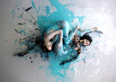 two white black and turquoise abstractly painted sexy young women on the floor, abstract body art painting. clipart