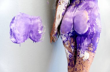 Beyaz, mor, eflatun, mor, menekşe boyalı, yaratıcı, soyut vücut sanatı ile boyanmış, duvarda renk izi olan seksi bir kadının kalçaları ve kalçaları.,