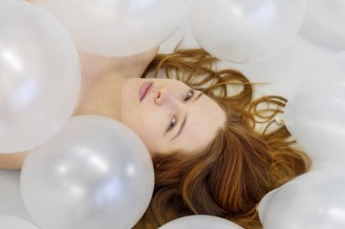 Yukarıdan portre sanat görüntüsü, güzel seksi bir kadın yüzü, kızıl saçlı, beyaz yanardöner balonlar, güzellik moda konsepti.