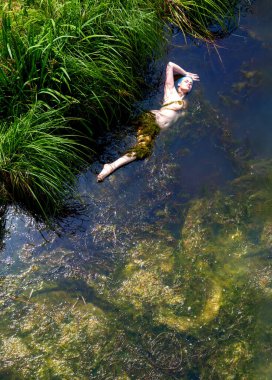 tutkulu, büyülü, seksi, baştan çıkarıcı, mavi saçlı deniz kızı yeşil yosun denizinde yüzüyor.
