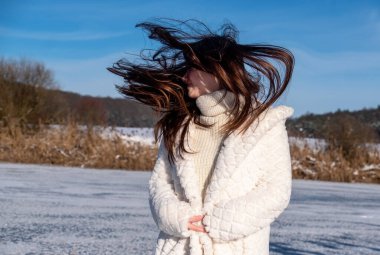 Güzel, seksi, baştan çıkarıcı, genç bir kadının portresi. Soğuk, karlı bir kış gününde, beyaz önlüklü, titrek saçlı, kopyalama alanı olan bir kadın.