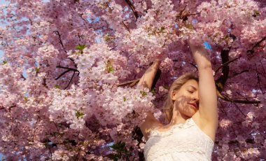 Şehvetli, baştan çıkarıcı, beyaz elbiseli, pembe çiçekli genç bir kadının portresi Nisan ayının bahar aylarında çiçek açıyor.