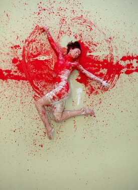 Bir kadın açık bir yüzeyde zarif bir şekilde yatar, üstü kırmızı ve beyaz renklerle kaplıdır. Vücudu güçlü bir sıçrama sanatının parçası haline gelir. Duyguları, hareketleri ve saf görsel enerjiyi harmanlar..