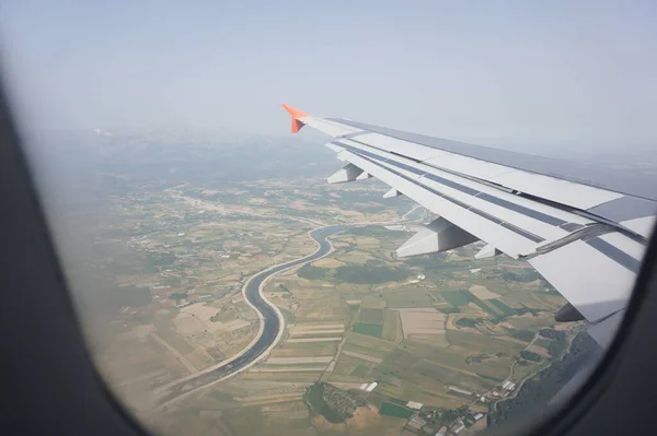 Bulutların üzerinde uçağın kanatları. Uçan bir uçağın penceresinden bak. Gökyüzünde uçarken manzaranın üstünde
