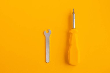 Sarı plastik saplı, parlak, izole sarı arka planda İngiliz anahtarı ve tornavida. Fotoğraf.