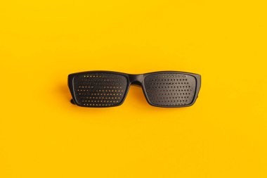 Gözleri iyileştirmek için gözlük. Sarı arkaplanda siyah plastik gözlük