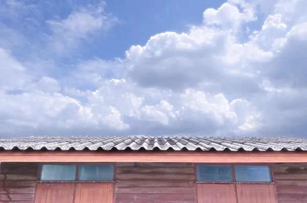 Cielo azul nublado brillante sobre el techo de la casa —  Fotos de Stock