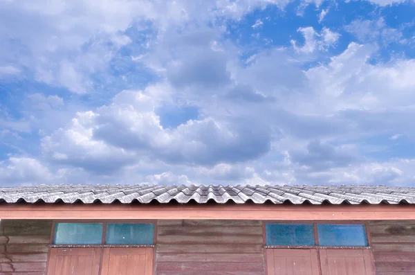 Cielo azul nublado brillante sobre el techo de la casa —  Fotos de Stock