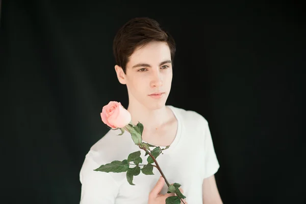 Handsome young man with single pink rose — Stockfoto