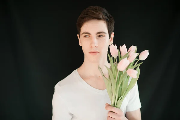 Handsome young man with pink tulips — Stockfoto