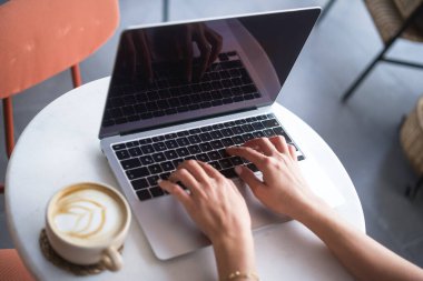 Kahve dükkanında bilgisayar kullanan bir kadın..