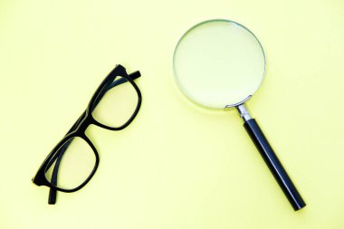 Sarı arka planda büyüteç ve gözlük.