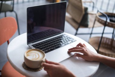 Kahve dükkanında bilgisayar kullanan bir kadın..