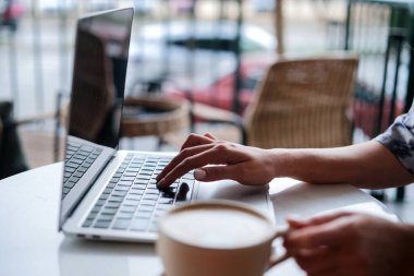 Kahve dükkanında bilgisayar kullanan bir kadın..