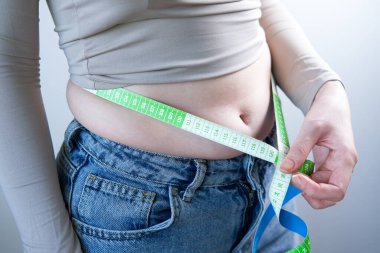 Bir kadının göbeğini sıkarken, belini mezurayla ölçerken yakın plan fotoğrafı..