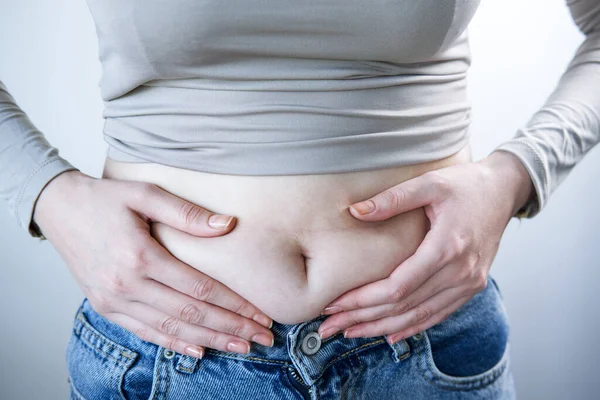 Göbeğini sıkan bir kadının yakın çekimi..