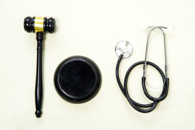 Açık yeşil arka planda yargıç tokmağı ve steteskobu..