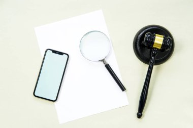 Yargıç tokmağı, akıllı telefon, kağıt ve büyüteç açık yeşil arka planda.