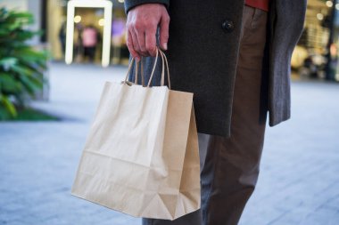 Adamın elinde kağıt bir alışveriş torbası var..