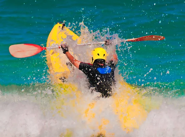 競争の中でカヤックは 前方に彼の腕で耳を保持大規模な 海の波を通過します ロイヤリティフリーのストック画像