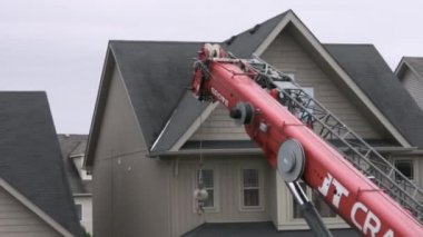Vinç operatörü vinç patlamasını evin ortasına çevirir ve evin arkasındaki yükün taşınmasını sağlar.