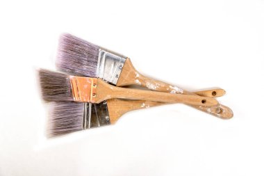 Üç düz, geniş boya fırçası beyaz bir arkaplanda yatıyor.