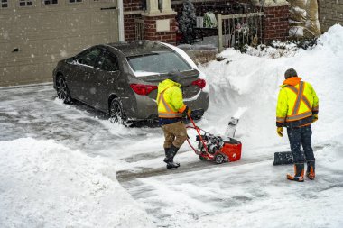 Bir gece fırtınasından sonra işçiler garajın girişinden kar temizliyor.