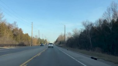 Sıcak bir yolda, ilkbaharın ilk günlerinde arabalar ve okul otobüsüyle.