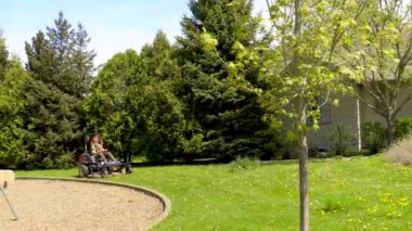 Küçük bir çim biçme makinesi arkasında toz bulutu bırakarak bir orman yolu boyunca sürdü.