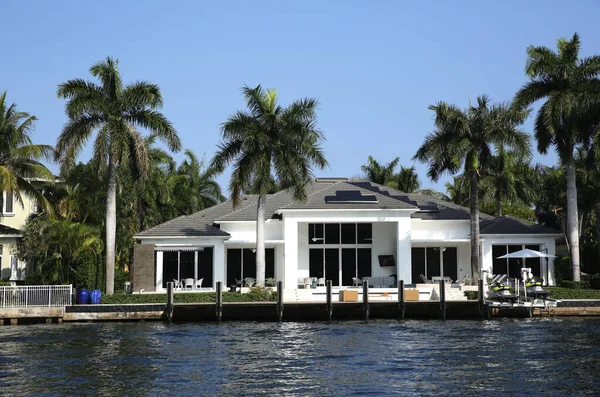 typical american house on the water of a canal or ocean or river surrounded by palm trees against a blue sky. resort house or residence