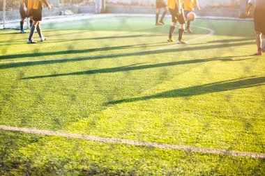 Bulanık futbolcu ile yeşil çimen futbol sahalarındaki güneş ışığına karşı futbolcu siluetine seçici bir odaklanma. Futbol ya da futbol akademisi.