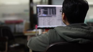 Programcının arkasına seçici odak, ekranda bulanık veri kodlaması olan programı geliştirmek için oturuyor. Bir yazılım geliştirme şirketinde programlama ve kodlama teknolojileri geliştirmek.