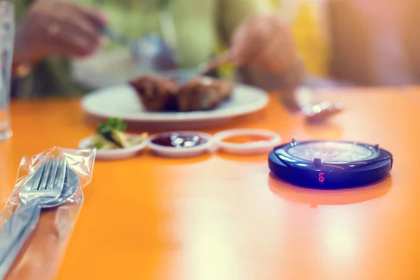 Wireless queue caller machine with blurry food. Queue paging wireless calling System with red light alarm for restaurant, coffee shop, cafe.