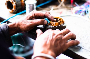 Elektrikli motor tamircisinin seçici odak noktası. Tamirci bakır bobini değiştirerek elektrik motorunu tamir ediyor..