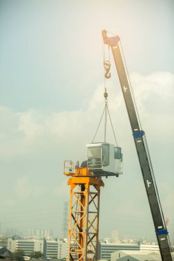 Mobil inşaat vincinin kolu, inşaat alanındaki yüksek binaların yapımında kullanıma hazır sarı vinç takıyor.