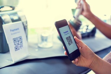 Müşteri, kafeteryada veya restoranda kahve yapan bulanık personelle QR kod ödeme etiketini taramak için akıllı telefon kullanıyor..