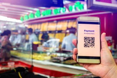 Bulanık altın mücevher dükkanı olan müşterinin elindeki akıllı telefon üzerindeki QR kod etiketine seçici odaklanarak para olmadan dijital ödeme yapmayı kabul etti. Qr kod ödeme kavramı.