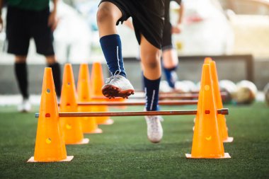Bulanık çocuk futbolcuyla külahları ayırmak ve engelleri aşmak için seçici bir odaklanma. Çocuk futbol antrenmanı.